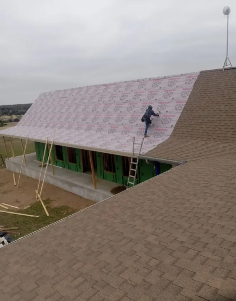 Worker preparing underlayment for a metal roof installation in Highland Park